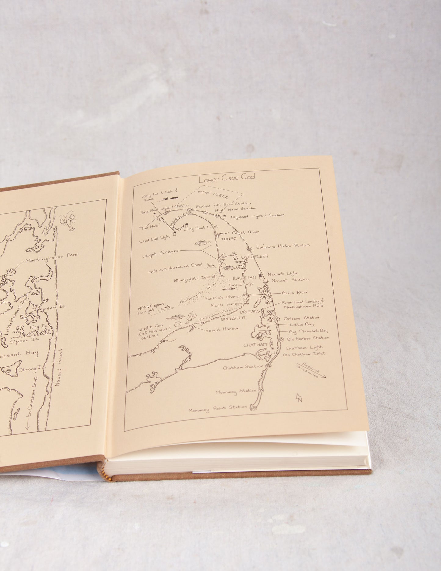 Open Cape Cod Fisherman book with maps and text on a light gray background
