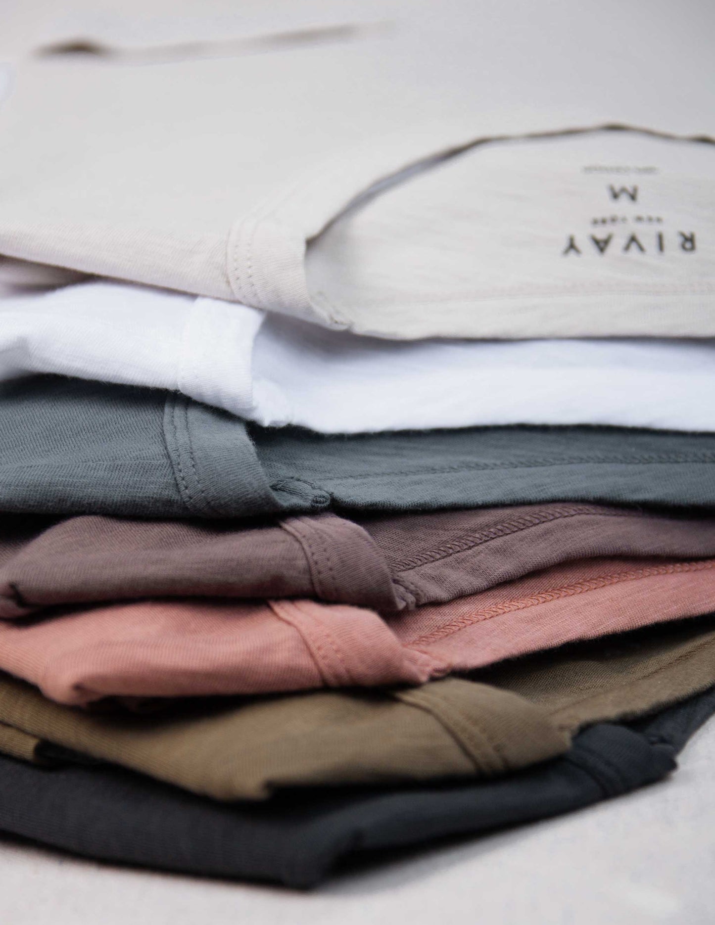 Stack of folded Rivay slub t-shirts in various colors